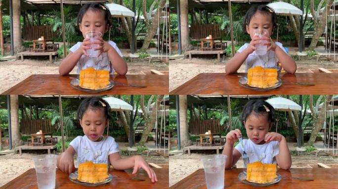 可爱的小女孩在木桌上喝冰冷的水。