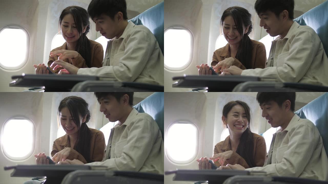 可爱的年轻夫妇在飞行中在智能手机上玩得开心