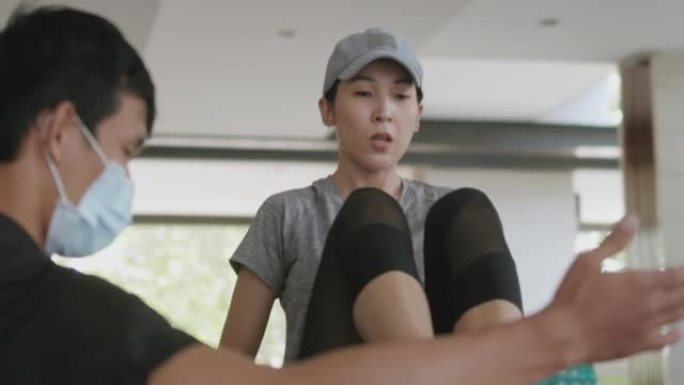 私人教练在家，东亚妇女要求私人健身课在家与私人教练在隔离和社会距离-股票视频