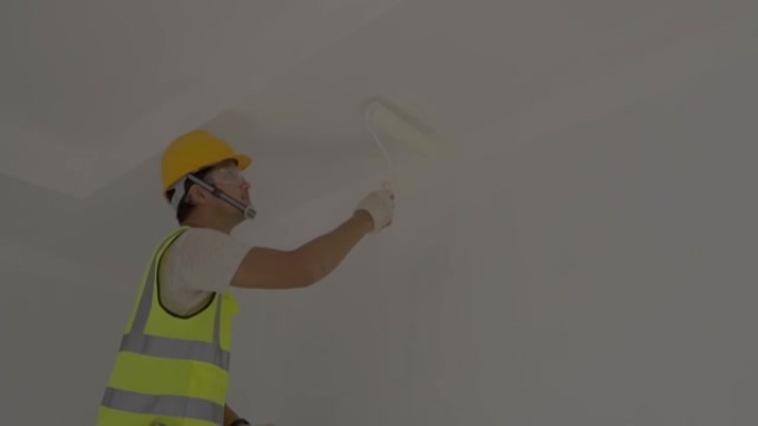 亚洲工人使用滚筒在施工现场粉刷墙壁。