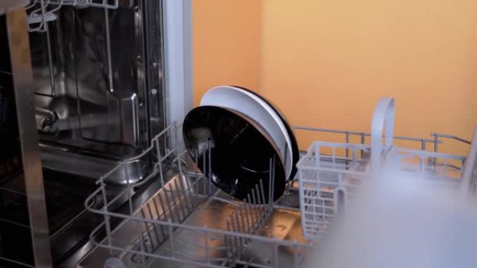 人类将未洗过的脏盘子放在洗碗机的架子上。4K