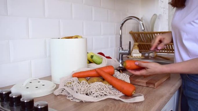 成年妇女站在厨房用蔬菜削皮器去皮胡萝卜。将废物堆肥到专用桶中。零浪费生活理念。有意识的蔬菜消费