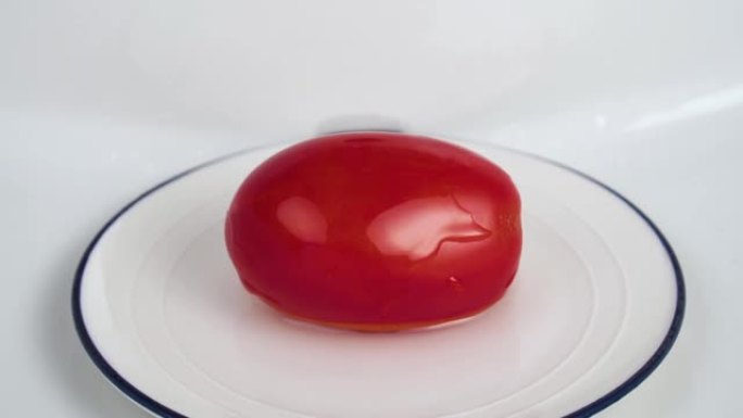 纯净水滴在白色盘子中的红色成熟番茄上