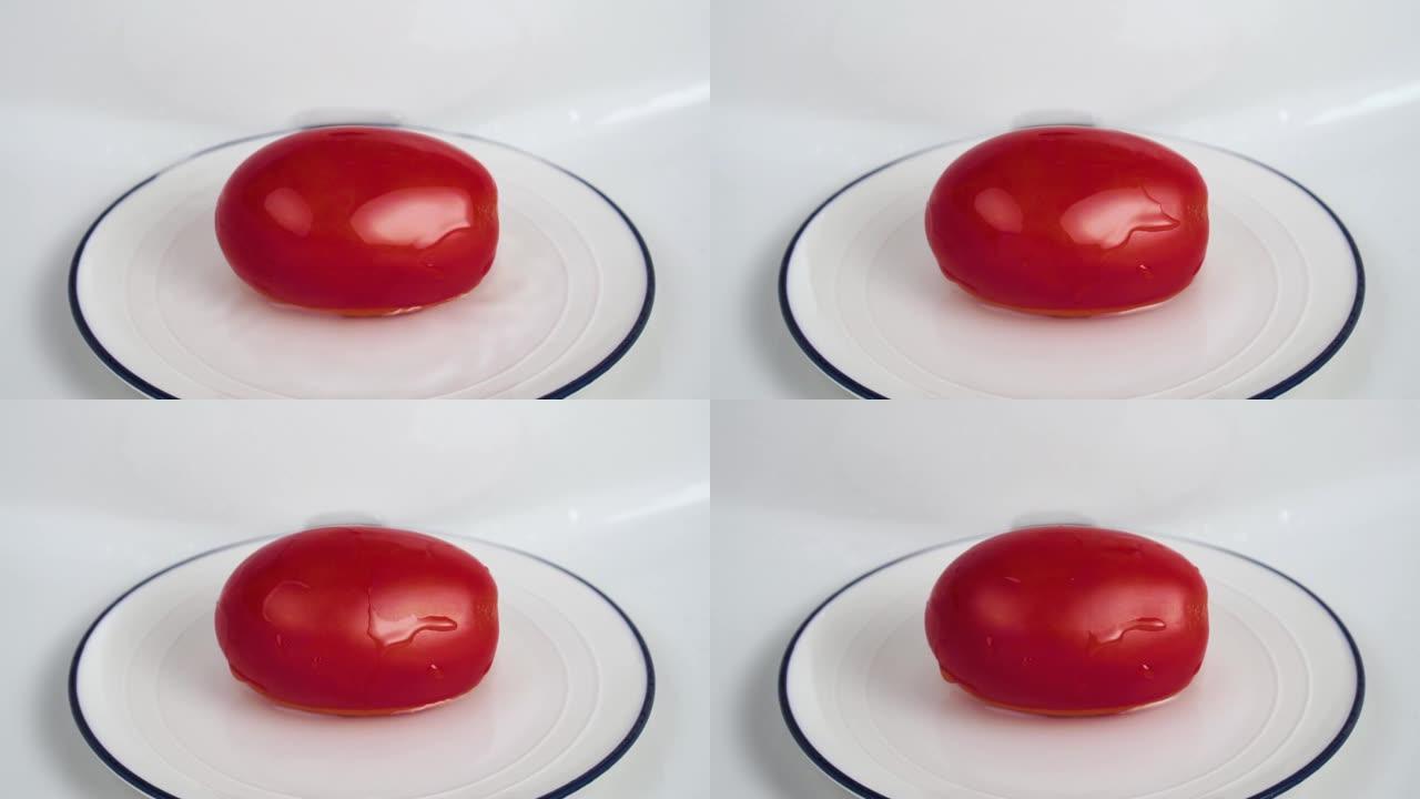纯净水滴在白色盘子中的红色成熟番茄上