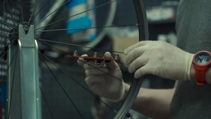 自行车车间的车轮矫直支架。机械师使用工具张紧速度轮轮缘中的辐条。小型企业自行车维修和服务主题。修整周