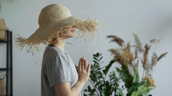 特写侧视图一位年轻女子以合十的姿势休息和放松，思考好想法，冥想和想象，均匀呼吸，在家里明亮舒适的房间