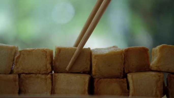 用筷子在自然背景下采摘鱼豆腐丁