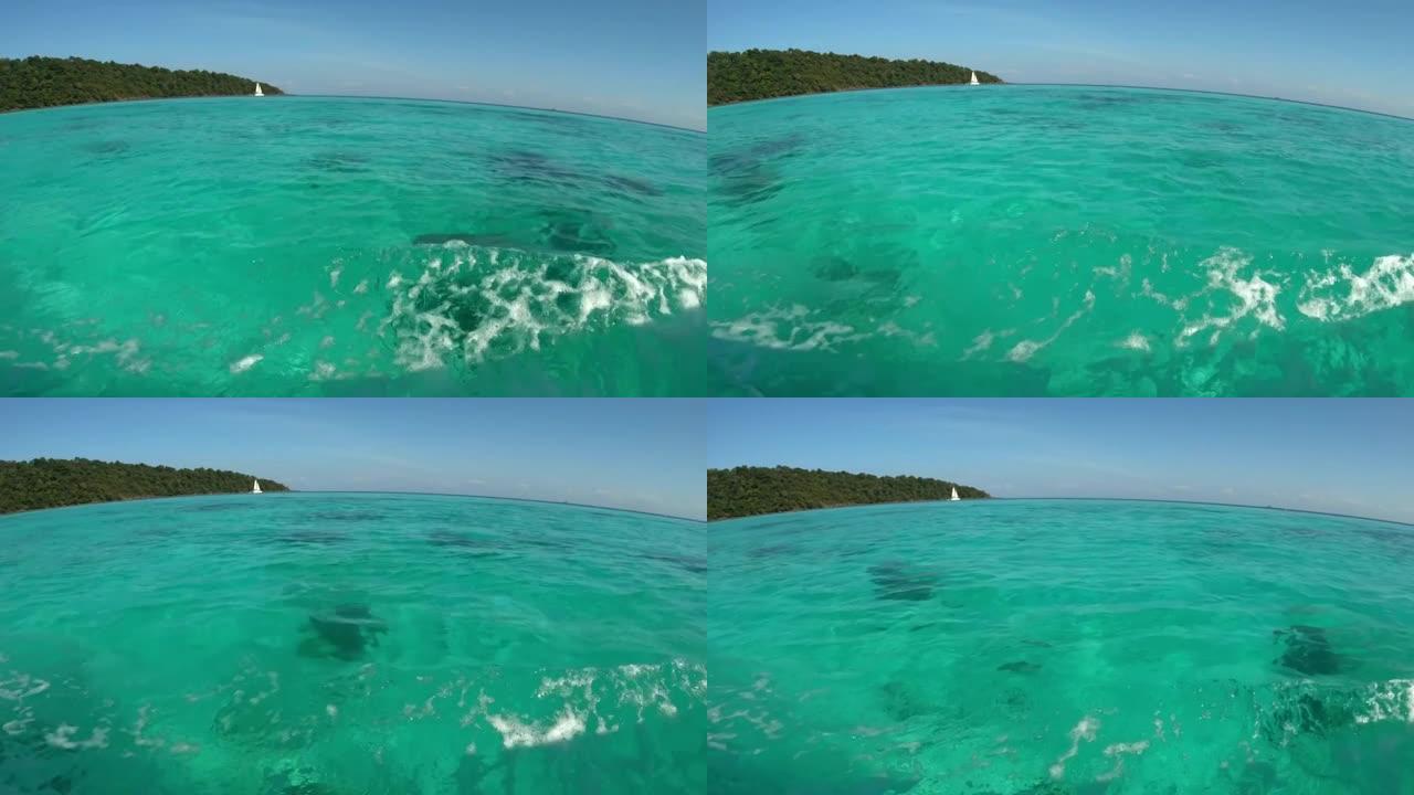 清澈的海水从海面到海底都是透明的。白天阳光的波动和反射照在蓝色液体上。小帆船在海上航行。广角视角水景