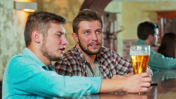 微笑无忧无虑的朋友喜欢在酒吧一起喝酒。一群快乐的年轻人喝冷生啤酒，聊天，在酒吧玩得开心。晚上笑着的人