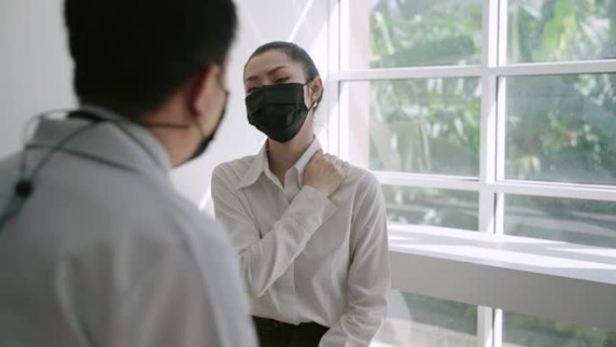 亚洲男性医生在诊所接受医疗咨询时戴着防护口罩与女性患者交谈。