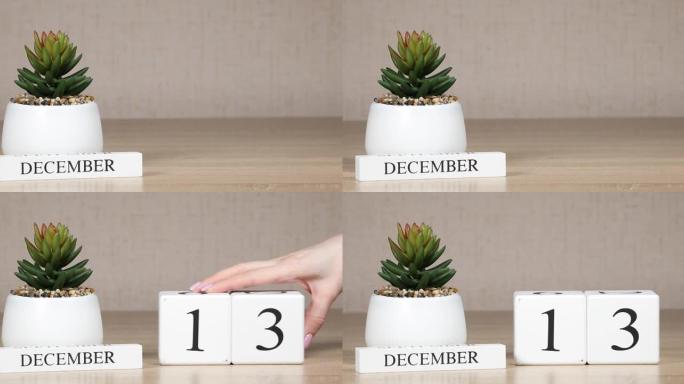 木制日历对12月13日来说是一个重要的事件，女人的手在日历上设置日期。冬季。