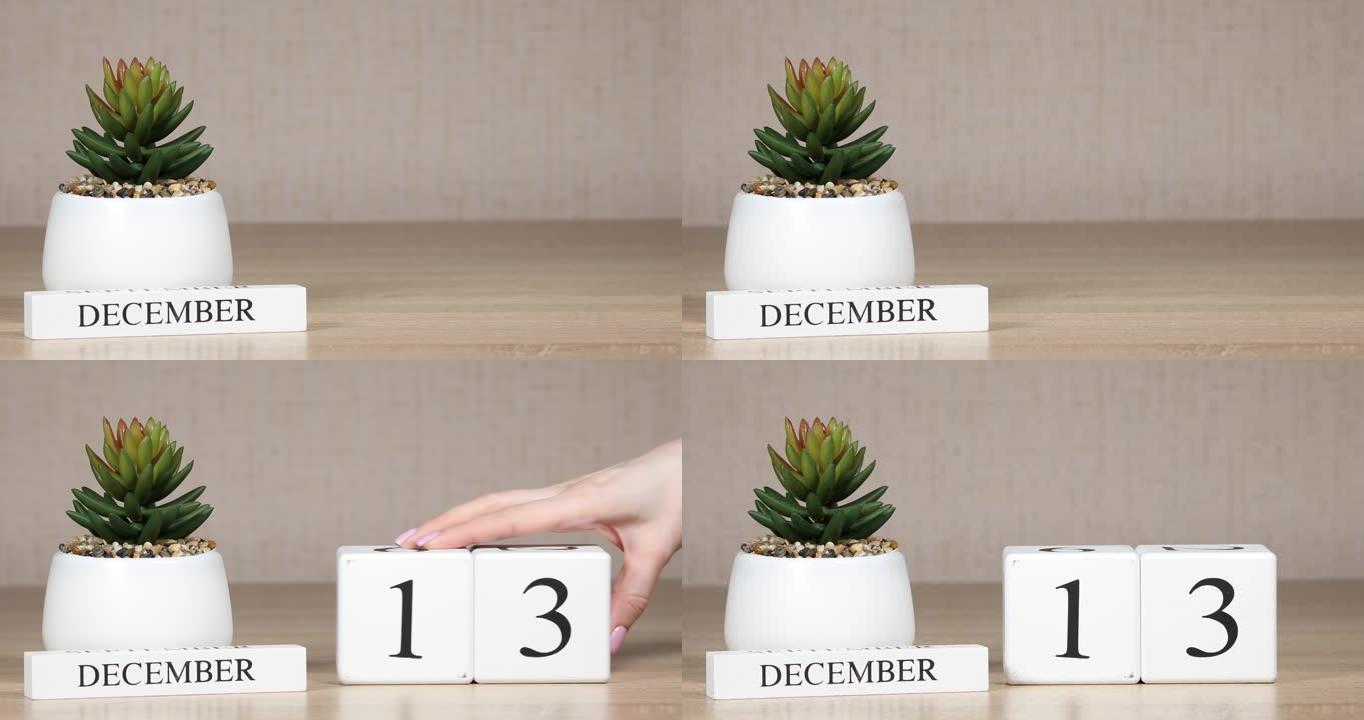 木制日历对12月13日来说是一个重要的事件，女人的手在日历上设置日期。冬季。