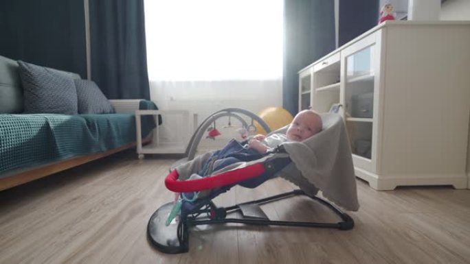 3个月大的男婴在婴儿保镖中，婴儿在客厅的摇椅中。