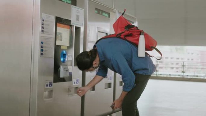 病毒流行期间，戴着防护口罩的年轻亚洲男性从自动售票机上捡钱-股票视频