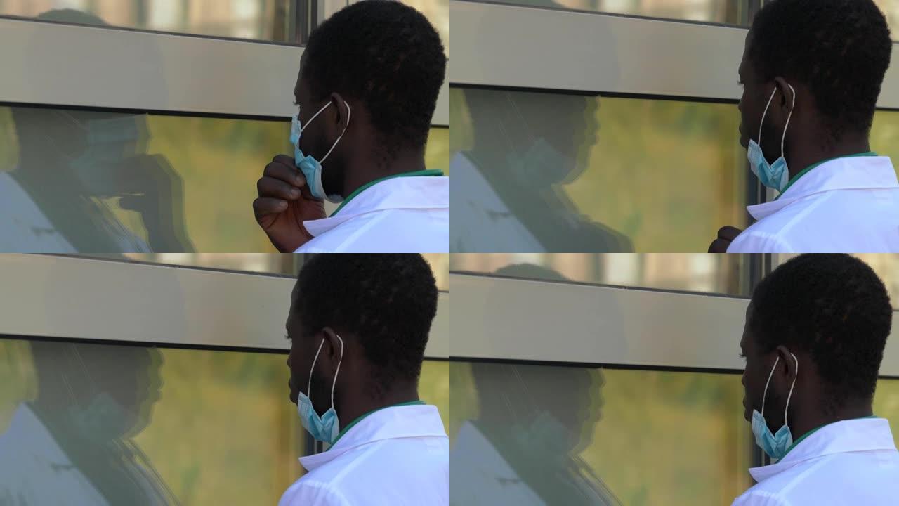 黑人医生看着玻璃上的倒影，拉下面具