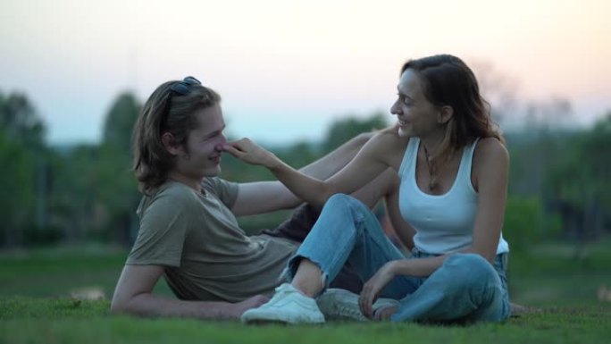 年轻的时髦夫妇早上在自然公园的草原乡村躺着聊天，日落在户外露营浪漫的时刻