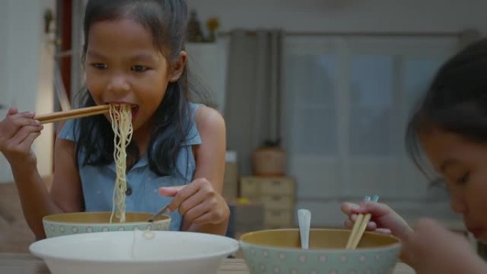 两名亚裔少女兄妹吃着泡面，在家里共享晚餐，幸福有加。