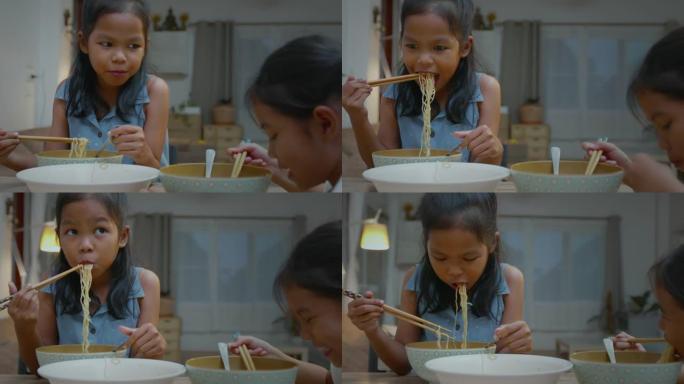 两名亚裔少女兄妹吃着泡面，在家里共享晚餐，幸福有加。