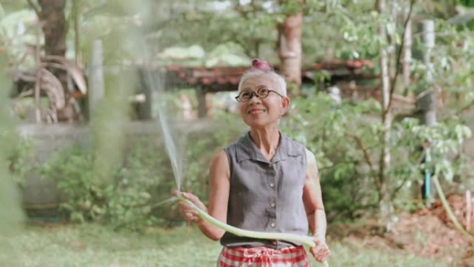 微笑的祖母在家浇灌观赏植物-库存视频