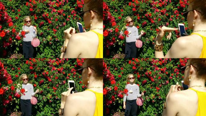 女孩在玫瑰园为妈妈摆姿势拍照