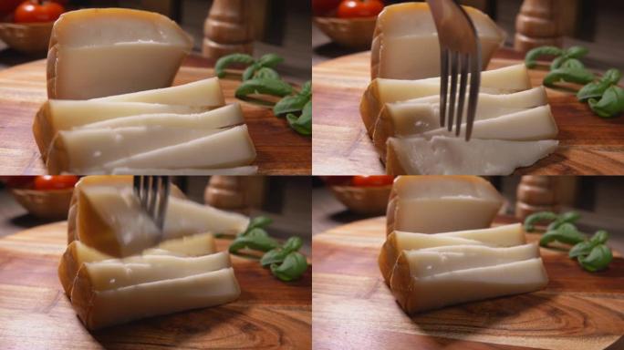 叉子从木板上拿了一块三角形的半硬羊奶酪