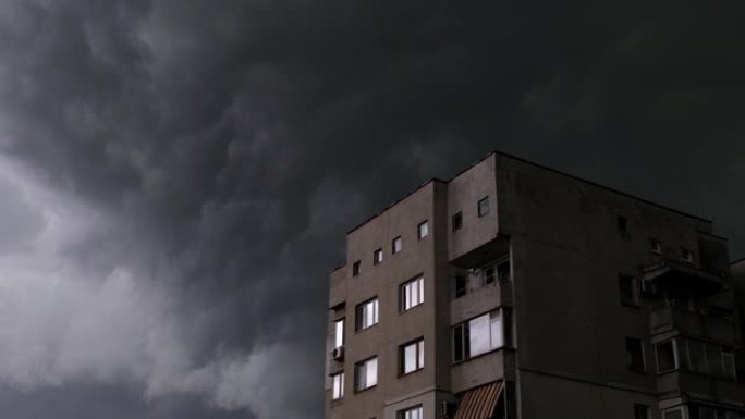快速移动的喜怒无常的黑暗暴风云与强风在城市与建筑在一边。即将来临的风暴