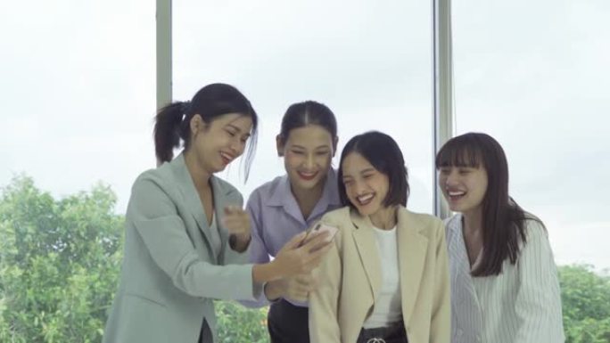 一群轻松的亚洲商界女性的肖像，人们见面，在办公室与同事的研讨会上看着移动智能手机设备。人们的生活方式