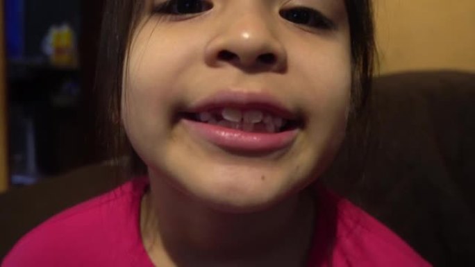 一个白人小女孩在4k的早晨在室内展示她刚掉下来的牙齿，黑色的头发和淡紫色的polo衫