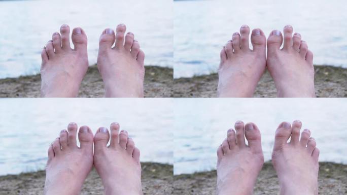 女人脚日光浴在沙滩上的河流，靠近水