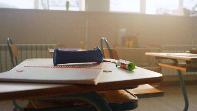 学校用品躺在教室的桌子上。桌子上的笔记本和铅笔盒