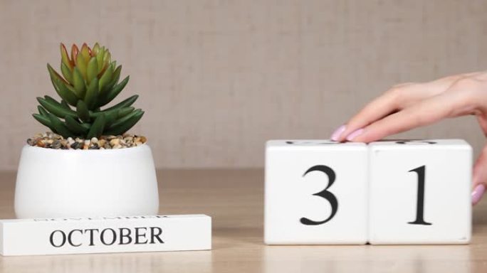 木制日历对10月31日来说是一个重要的事件，女人的手在日历上设置日期。秋季。