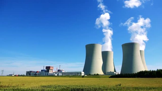 工厂 (核电站)-建筑物和烟囱烟雾的特写镜头-有植物和蓝天的田野