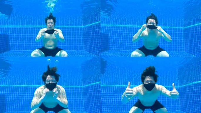 新型冠状病毒肺炎日冕病毒大流行期间，亚洲男子戴着黑色面罩，在游泳池水下竖起大拇指。