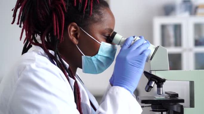 在实验室中使用显微镜的非洲女科学家工人的侧视图的4k视频