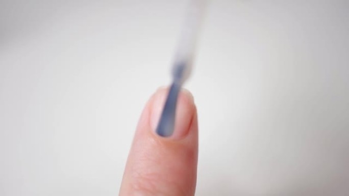 指甲特写。用刷子在指甲板上涂上透明的清漆。应用
