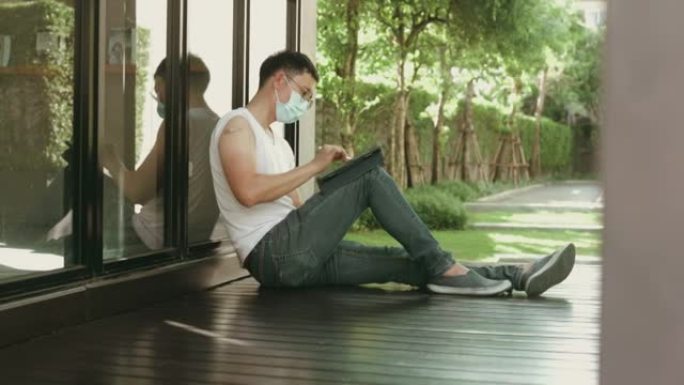 新冠肺炎疫情视频直播期间，一名戴着防护口罩的活跃男子在接种疫苗后坐在关闭的图书馆外工作