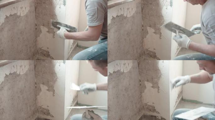 熟练的修理工在工作服上用金属抹刀和白色石膏糊在窗户下抹平破旧的水泥墙，用抹刀和腻子粉刷平整墙面。墙壁