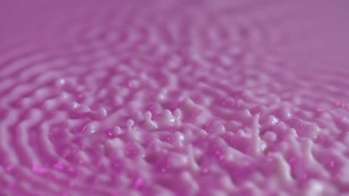 振动和共振。声波在牛奶紫色表面的分布。当被不同频率的振动激发时，乳状流体的圆圈和波纹。慢动作。特写