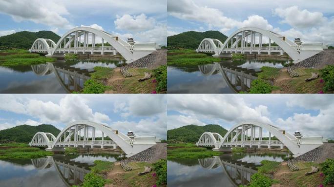 泰国南蓬的Tha Chomphu白色桥的时间流逝，有湖泊或河流，森林树木和绿山。自然景观背景。旅游景