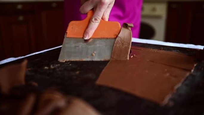 顶部视频显示了一个巧克力女人在大理石桌子上搅拌回火的液体黑巧克力，用蛋糕刮刀将其冷却并准备美味的巧克