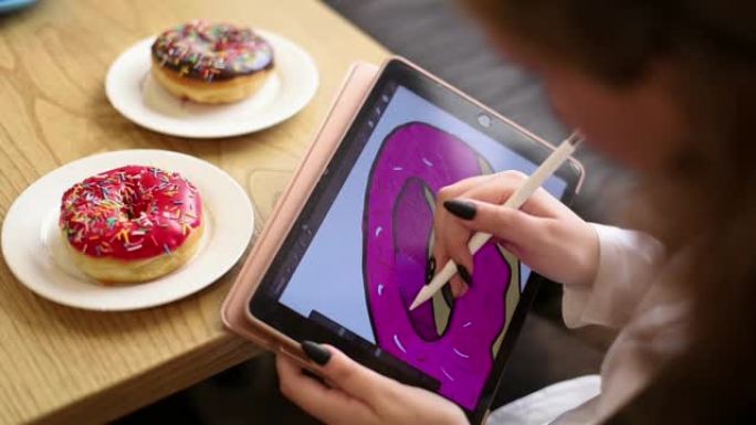 女人的手在电子平板上画一个甜甜圈。