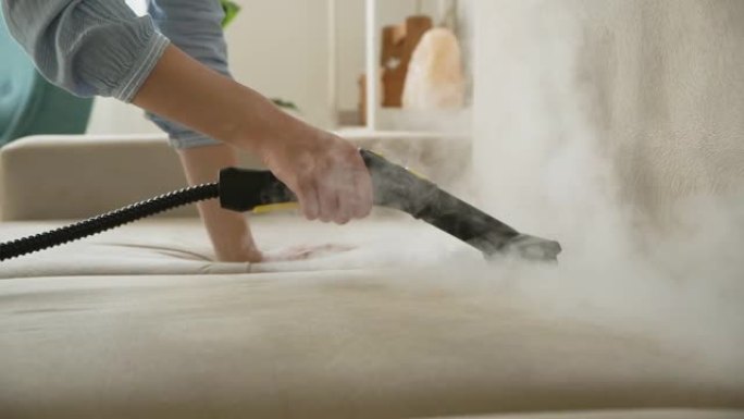 用蒸汽清洁器手清洁沙发，家庭清洁概念。