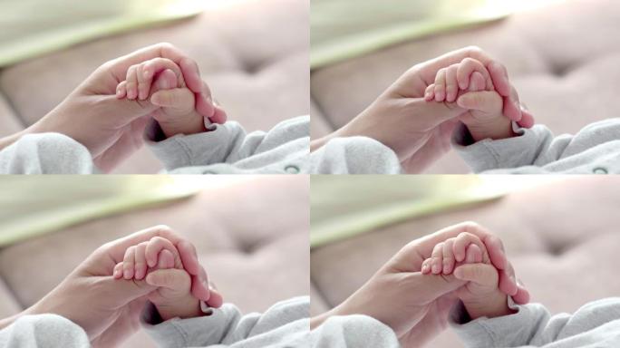 4k新生婴儿牵着妈妈，妈妈抚摸婴儿的小手使他感受到她的爱，温暖和安全。生育，家庭，生育概念