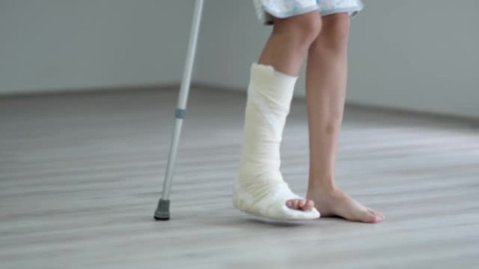 用石膏石膏折断腿的年轻女子试图在客厅用拐杖走路。身体伤害、骨折和事故，