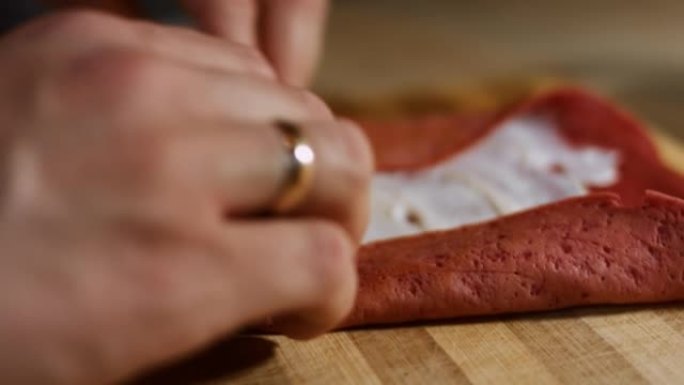 薄薄的美味彩色煎饼。女人的手将鲑鱼片放在木板上涂上奶油奶酪的红色煎饼上的宏观视图。滚动煎饼。4k视频