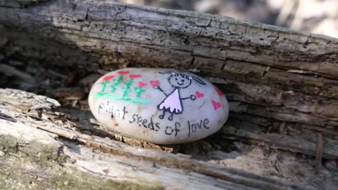 爱情信息的植物种子和卡通小女孩画在隐藏的善良岩石上