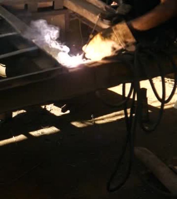 垂直工业工厂机械工人man钢焊工在工业工厂戴焊接面罩焊钢。