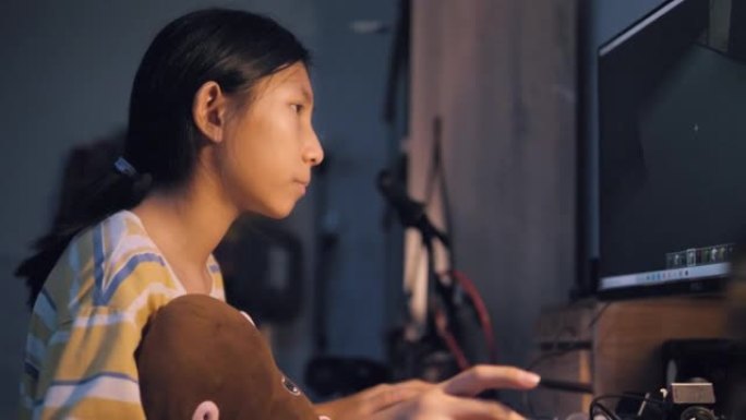 亚洲女孩在晚上在家玩电脑在线游戏，生活方式概念。