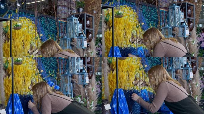 一名妇女触摸植物的蓝色，吸入植物的气味，在相机上分享了她的印象。这个女人被各种器皿和玻璃容器中的植物