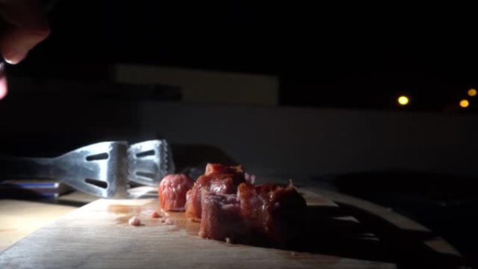 香肠大块的特写镜头在桌子上蒸，并用手抓住晚上在4k吃饭